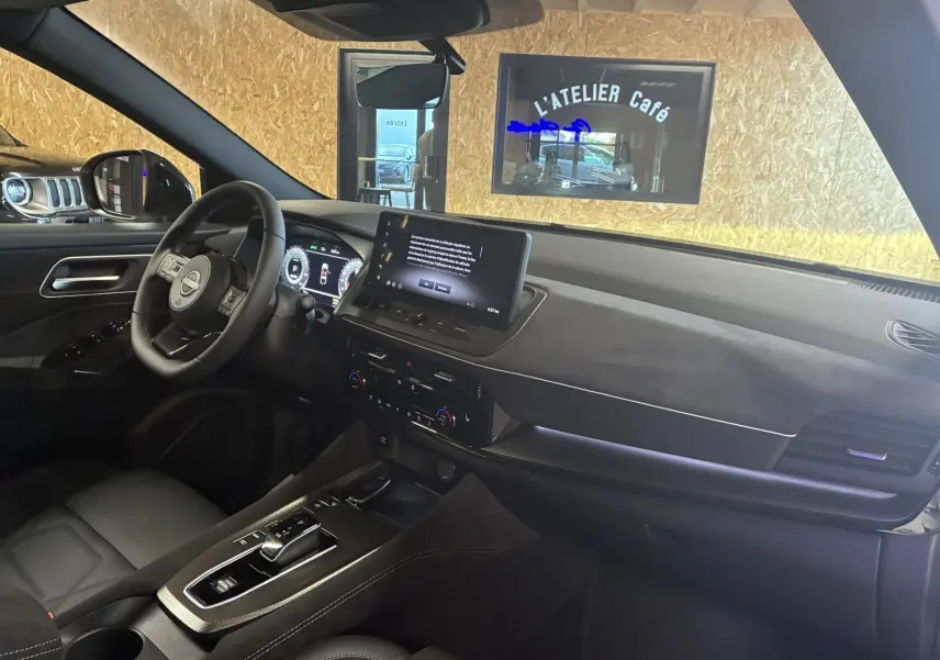 Intérieur du Nissan Qashqai 2025 vu côté conducteur, tableau de bord moderne avec écran tactile et sellerie noire élégante.