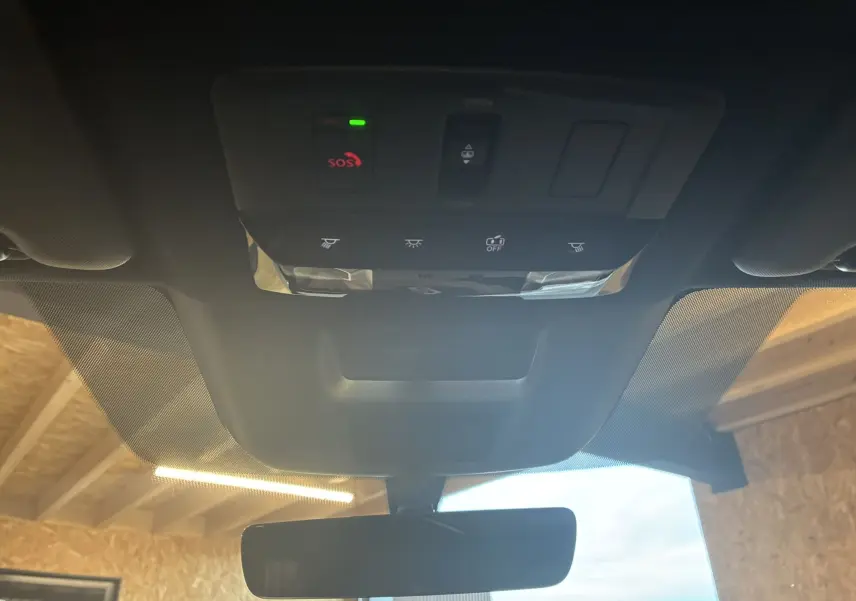 Vue intérieure du toit ouvrant et du panneau de commandes avec bouton SOS du Nissan Qashqai blanc nacré 2025.