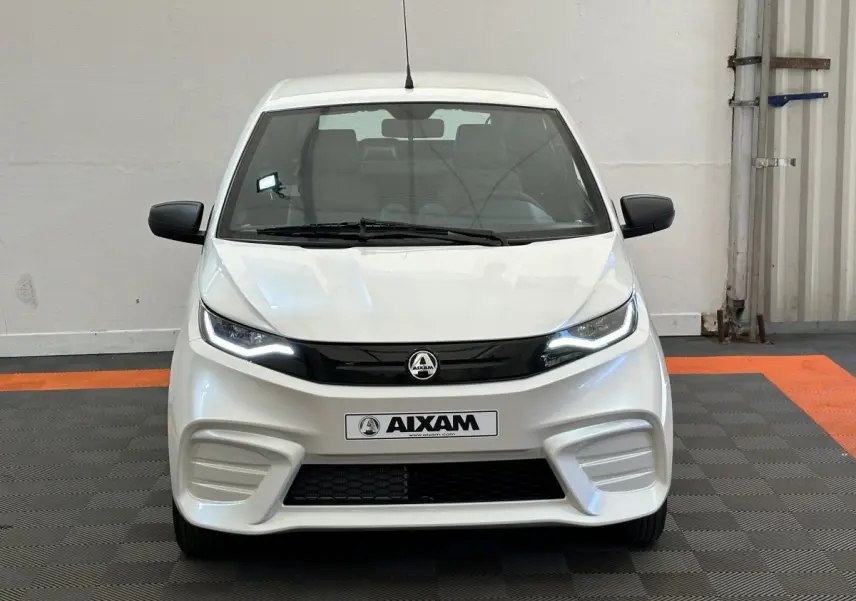 Vue frontale d'une Aixam Ambition E City Pack blanche 2025 avec phares LED et rétroviseurs noirs côté conducteur équipé caméra.