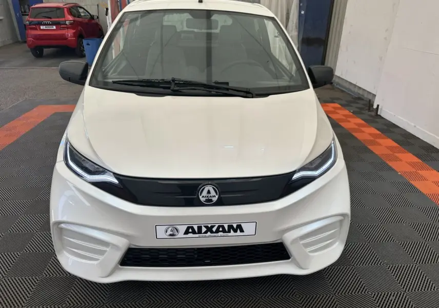 Vue frontale d'une Aixam Ambition E City Pack blanche 2025 avec calandre noire et phares LED distinctifs.