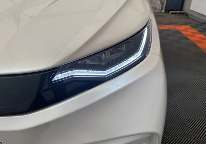 Gros plan sur le phare avant droit blanc de l'AIXAM AMBITION E CITY PACK 2025 avec éclairage LED distinctif.