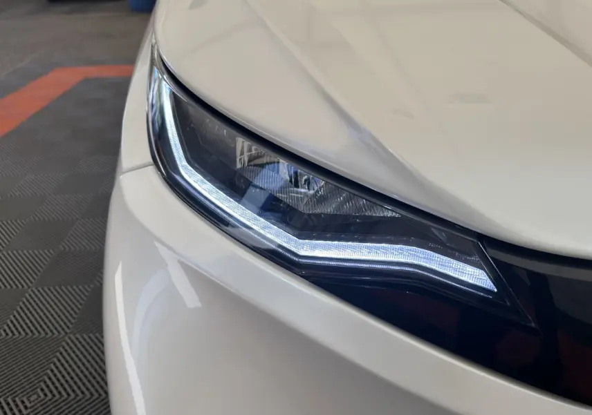 Gros plan sur le phare avant droit blanc de l'AIXAM AMBITION E CITY PACK 2025 avec éclairage LED distinctif.