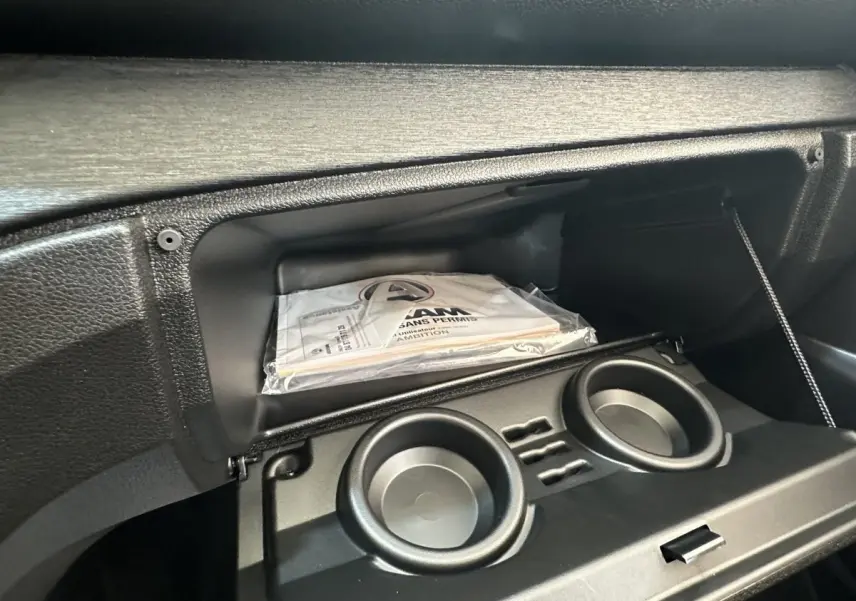 Intérieur de la boîte à gants ouverte de l'AIXAM AMBITION E CITY PACK 2025 avec documentation visible.