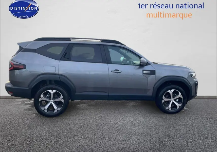 Vue latérale droite du Dacia Bigster gris schiste 2025 avec jantes alliage diamantées et barres de toit noires.