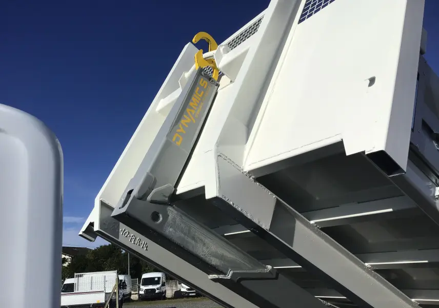 Gros plan sur le bras de levage blanc et gris du Ford Transit Chassis Cabine blanc, benne relevée sous un ciel bleu.