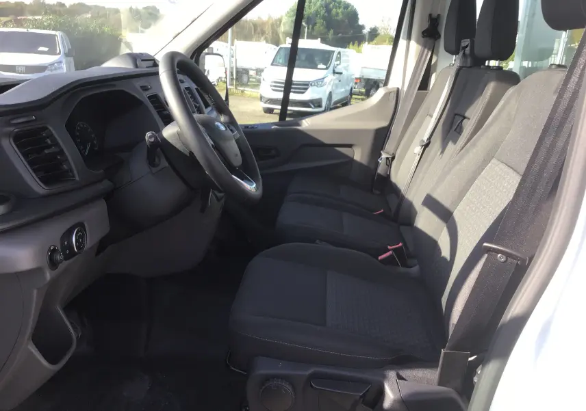 Vue intérieure côté conducteur du Ford Transit Chassis Cabine blanc 2025, montrant les sièges avant et le tableau de bord.