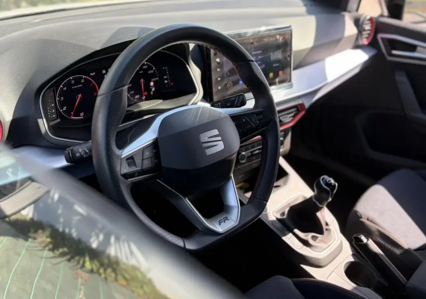 Vue intérieure centrée sur le volant FR et la console centrale avec levier de vitesse manuelle d'une SEAT Ibiza blanche.