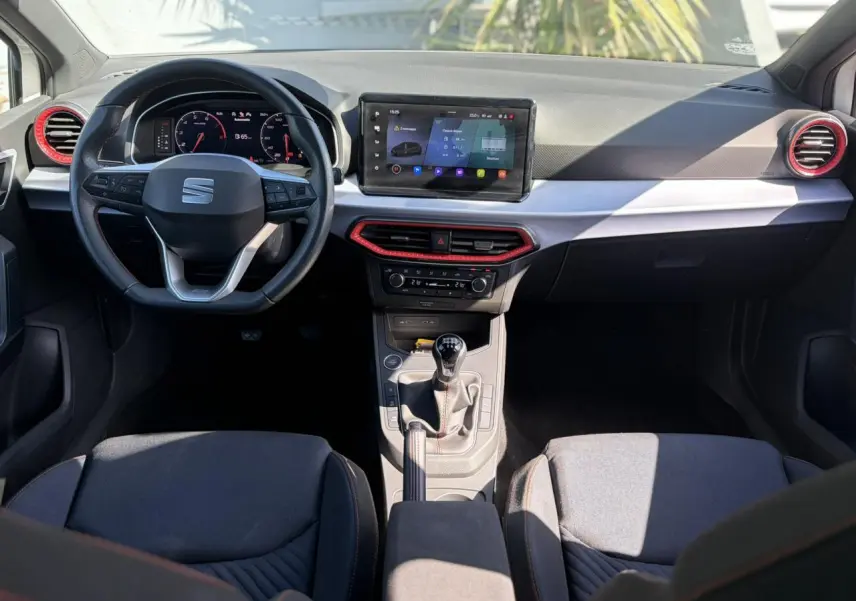 Intérieur SEAT Ibiza TSI 115 FR 2025 vu de face, tableau de bord avec écran tactile et détails rouges autour des aérateurs.