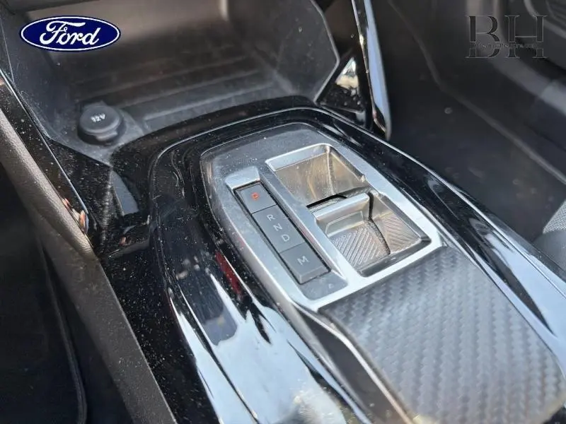 Le véhicule visible sur l'image n'est pas un Peugeot 2008 mais semble être un modèle Ford, comme l'indique le logo Ford visible. L'image montre un détail intérieur en gros plan de la console centrale avec la commande de boîte automatique.