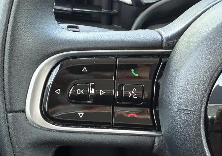 Gros plan sur les commandes multifonctions noires du volant de la Fiat 500 électrique blanche 2023.