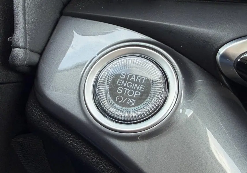 Gros plan sur le bouton Start Engine Stop gris brillant du tableau de bord de la Fiat 500 électrique blanche 2023.