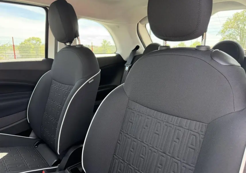 Gros plan sur les sièges avant noirs de la Fiat 500 e 118ch MY23 avec motif monogramme Fiat et surpiqûres blanches.
