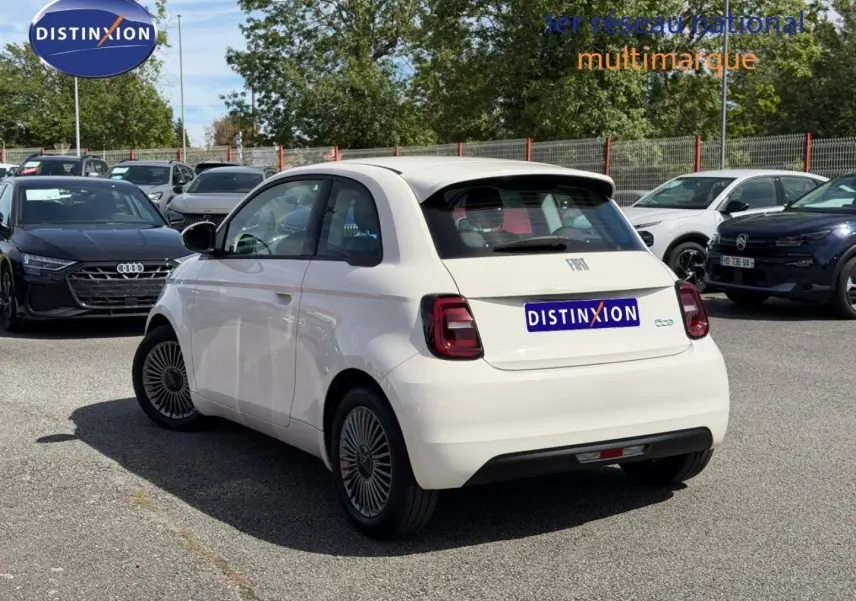 Vue 3/4 arrière droite d'une Fiat 500 électrique blanche 2023 avec feux arrière LED et becquet arrière.