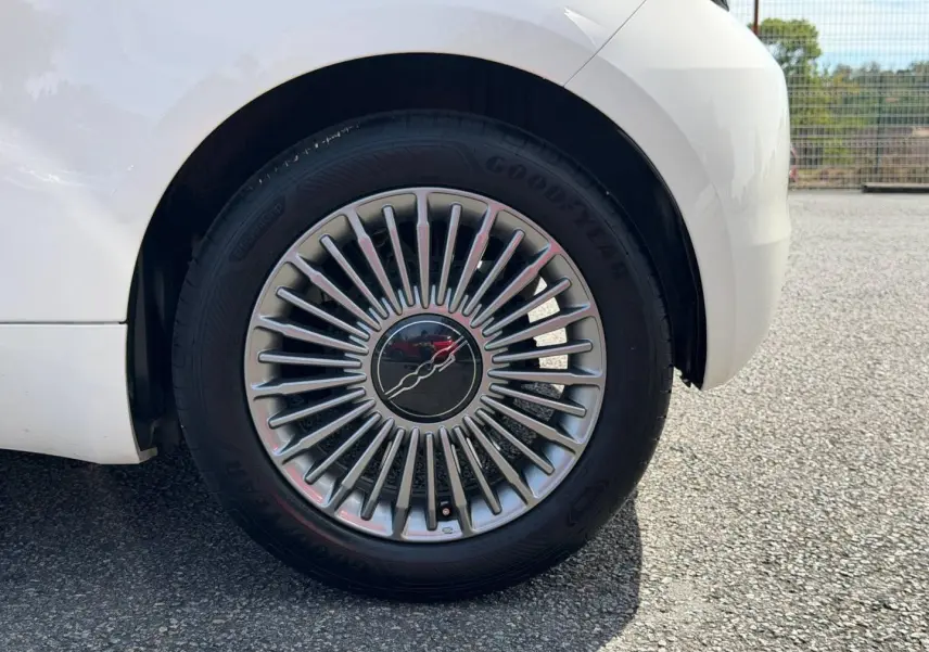 Gros plan sur la roue arrière droite blanche d'une Fiat 500 électrique 2023 avec jante à rayons fins argentés.