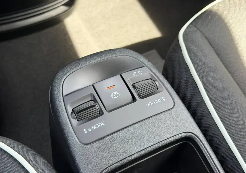 Gros plan sur la console centrale de la Fiat 500 électrique blanche 2023, avec commandes e-Mode et volume entre les sièges noirs.