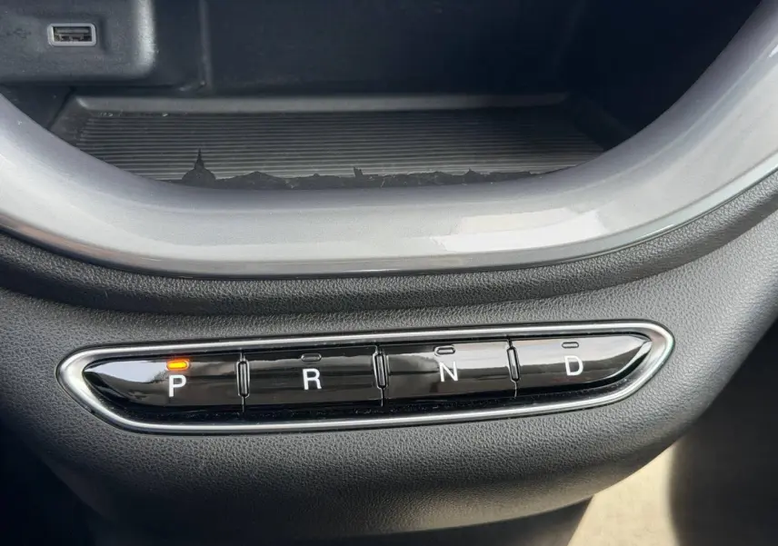 Gros plan sur la commande de boîte automatique noire avec indication orange sur "P" dans une Fiat 500 électrique blanche.