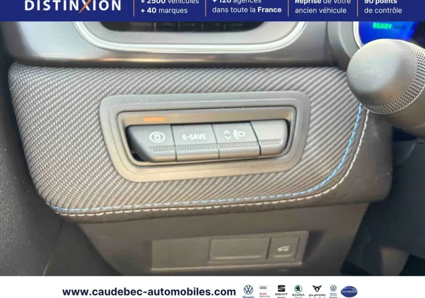 Gros plan sur les commandes E-Save et éclairage intégrées dans la console carbone avec surpiqûres bleues du Renault Symbioz gris.