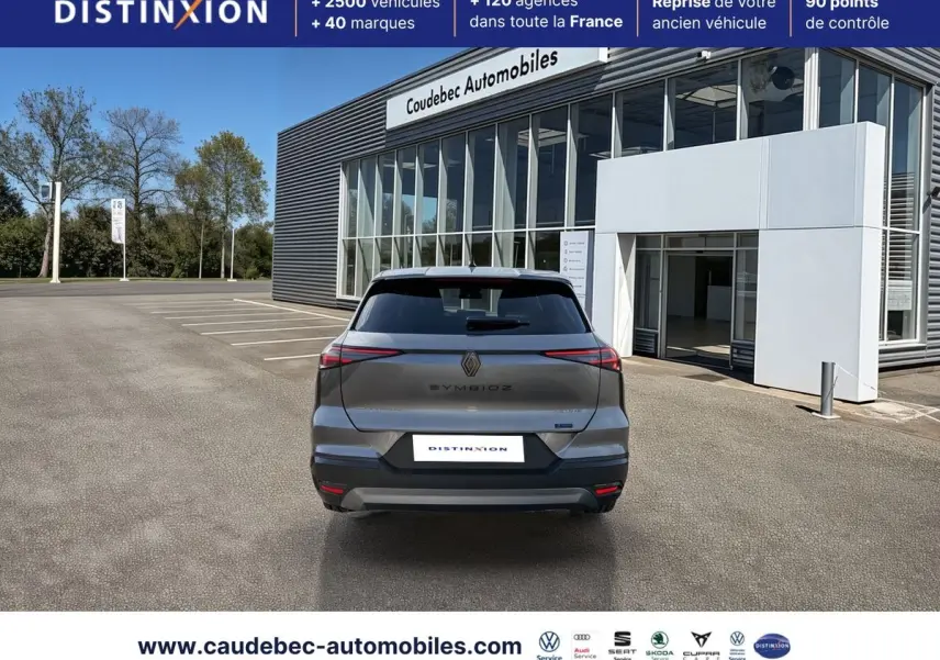 Vue arrière d’un Renault Symbioz gris métallisé garé devant un bâtiment moderne avec vitres larges.
