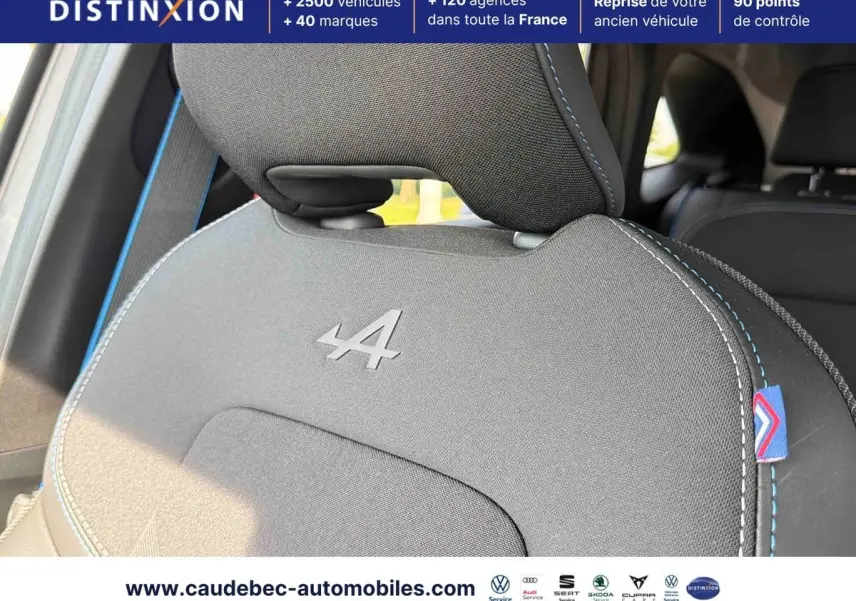 Gros plan sur l'appui-tête avant gris avec logo Alpine brodé et surpiqûres bleues dans l'habitacle du Renault Symbioz.