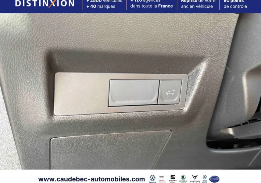 Détail du bouton d'ouverture du hayon sur la planche de bord grise de la Renault Symbioz E-Tech hybride 2026.