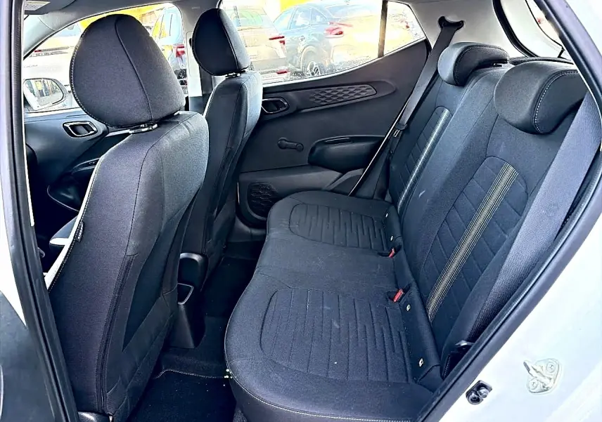 Vue intérieure côté droit sur la banquette arrière en tissu noir de la Hyundai i10 blanche 2024.