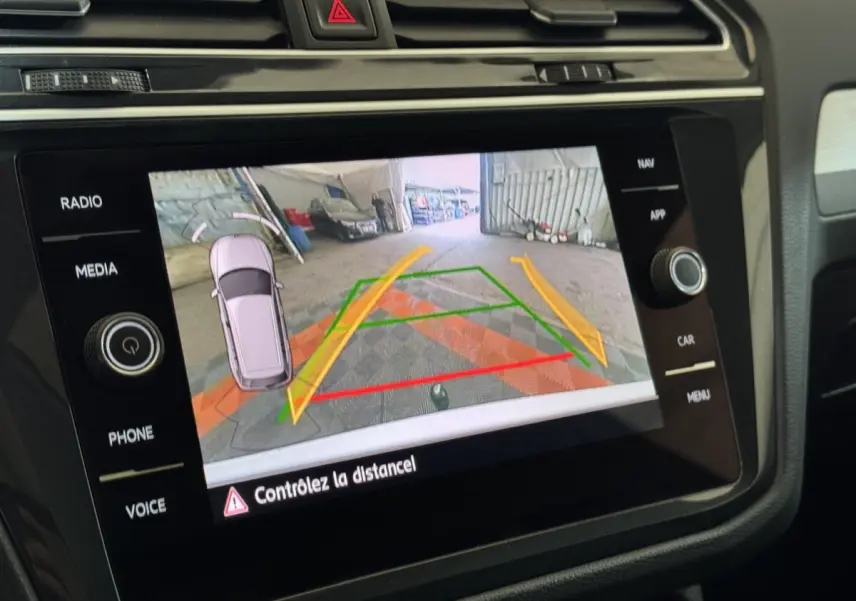 Écran tactile intérieur du Volkswagen Tiguan blanc montrant la caméra de recul avec guidage de trajectoire coloré.