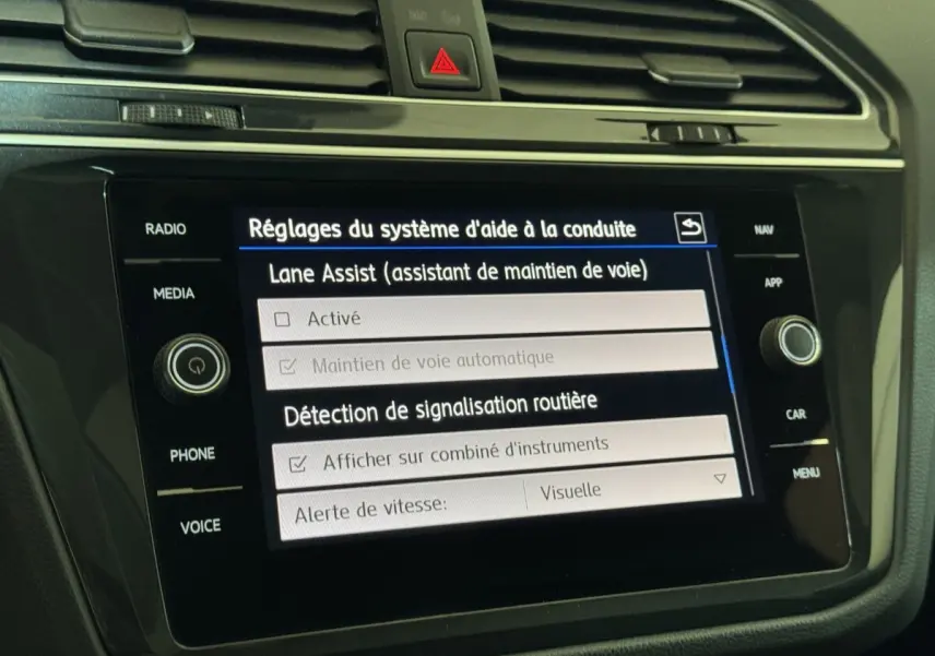 Écran tactile central noir du Volkswagen Tiguan blanc 2020 affichant les réglages d'aide à la conduite.