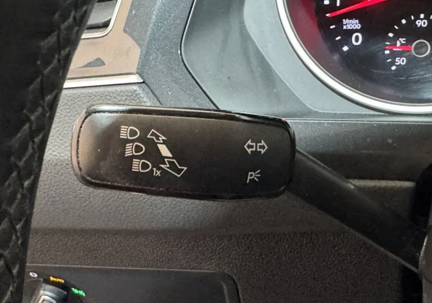 Gros plan sur la commande de clignotants et feux à gauche du volant du Volkswagen Tiguan blanc 2020.