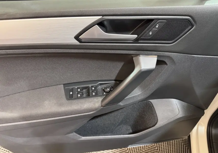Vue intérieure côté gauche de la porte avant d'un Volkswagen Tiguan blanc avec commandes de vitres et verrouillage.