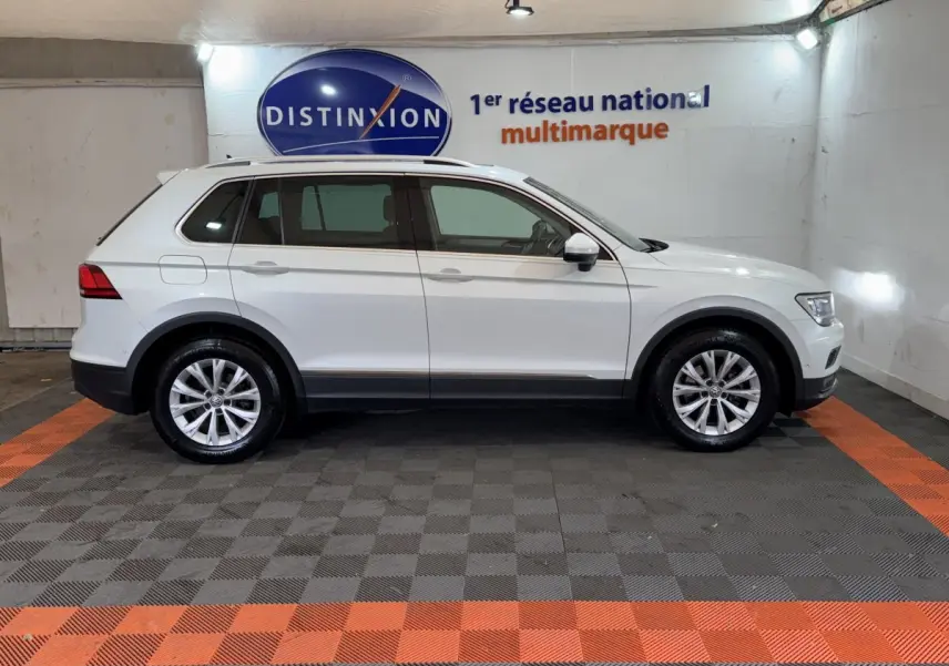 Profil côté gauche d'un Volkswagen Tiguan blanc 2020 garé en intérieur sur sol à damiers gris et orange.