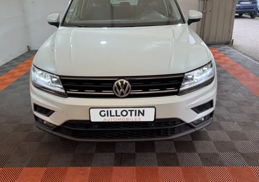 Vue frontale d'un Volkswagen Tiguan blanc 2020 avec phares LED allumés et calandre noire brillante.