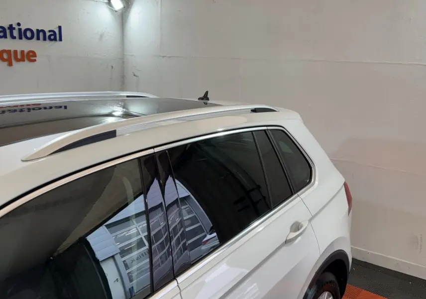 Vue côté droit arrière du Volkswagen Tiguan blanc 2020 avec barres de toit et vitres teintées.