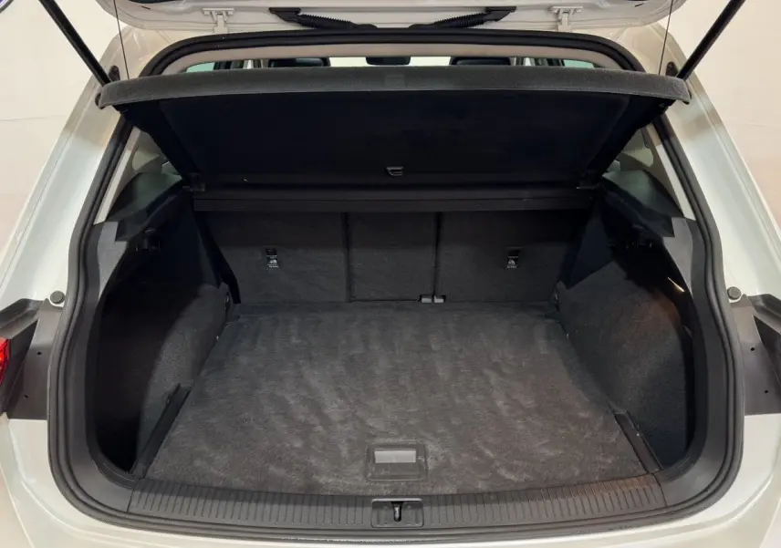 Coffre ouvert d'un Volkswagen Tiguan blanc 2020 vu de l'arrière, montrant un espace de chargement spacieux et propre.