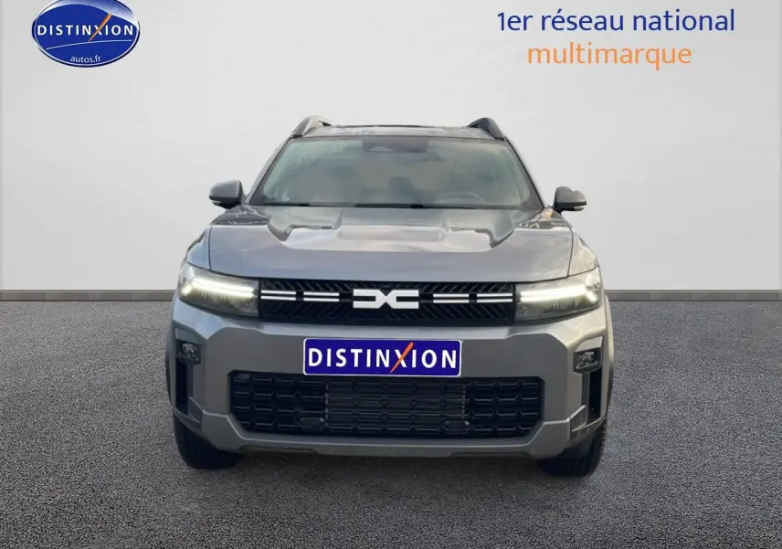 Vue avant du Dacia Bigster gris schiste avec calandre noire et phares LED allumés sur fond neutre.