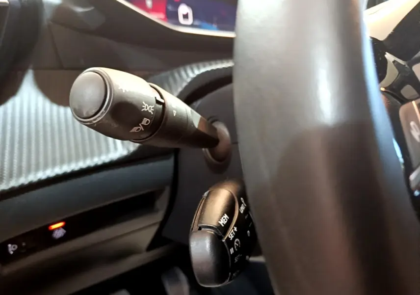 Gros plan sur le volant cuir et les commandes multifonctions du Peugeot 208 jaune, vue côté conducteur.