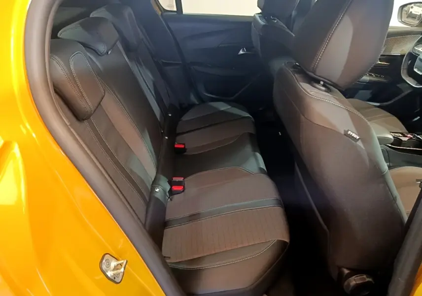 Vue intérieure côté gauche montrant la banquette arrière noire et le siège avant d'une Peugeot 208 jaune 2023.