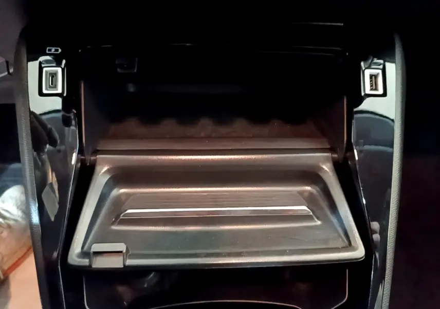 Vue rapprochée de la console centrale noire avec ports USB ouverts dans une Peugeot 208 jaune 2023.