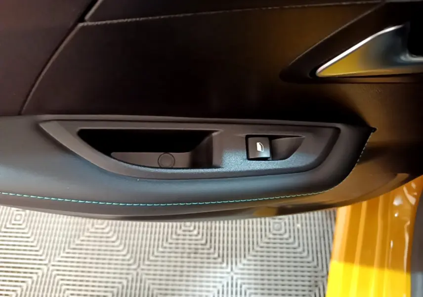 Gros plan sur la poignée intérieure et bouton de verrouillage de la porte côté conducteur d'une Peugeot 208 jaune.