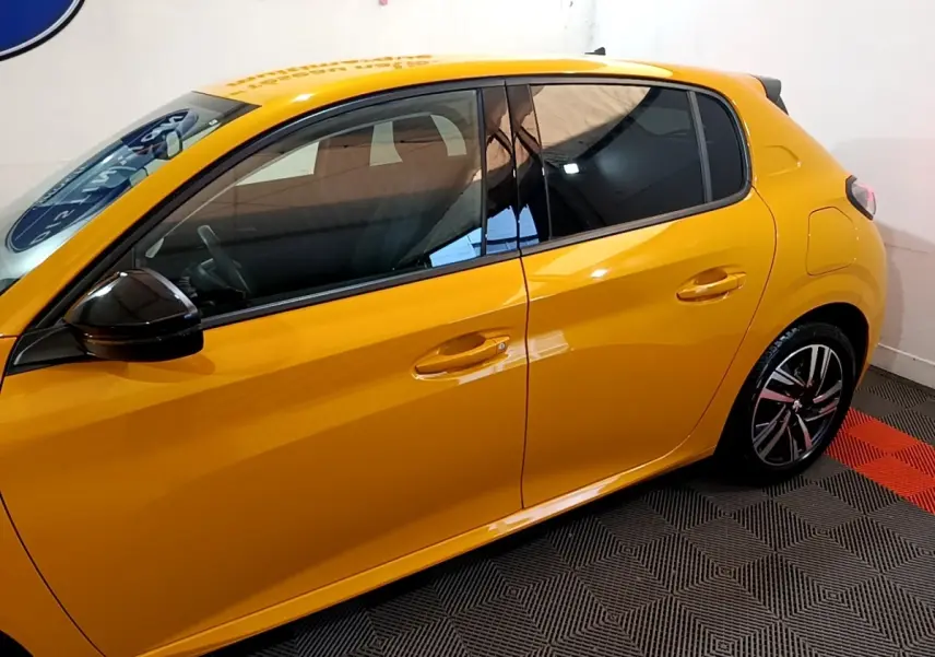 Vue latérale droite d'une Peugeot 208 jaune vif avec rétroviseur noir et jantes alliage modernes.