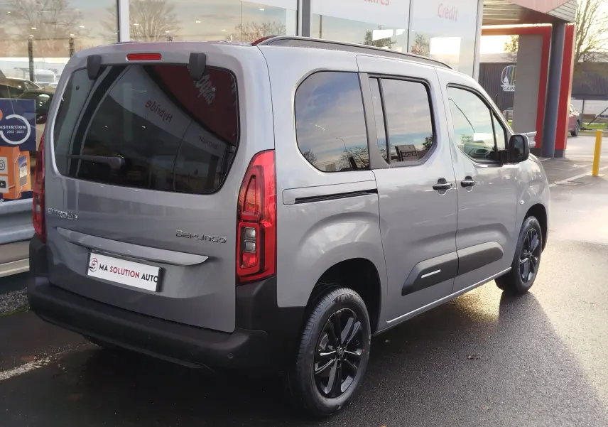 Vue 3/4 arrière droite d'un Citroën Berlingo gris acier 2025 avec vitres teintées et jantes noires.