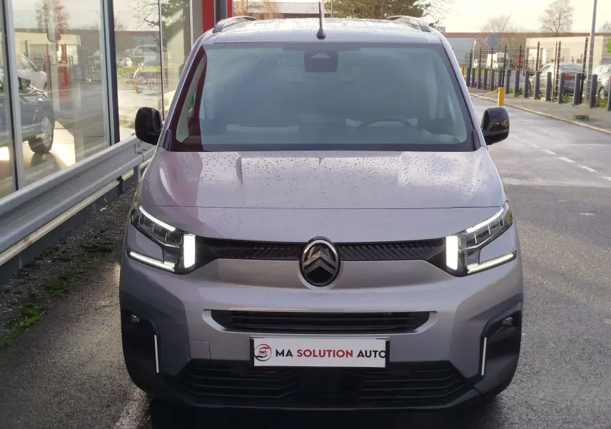 Vue avant d'un Citroën Berlingo gris acier 2025 avec phares LED allumés et calandre noire distinctive.