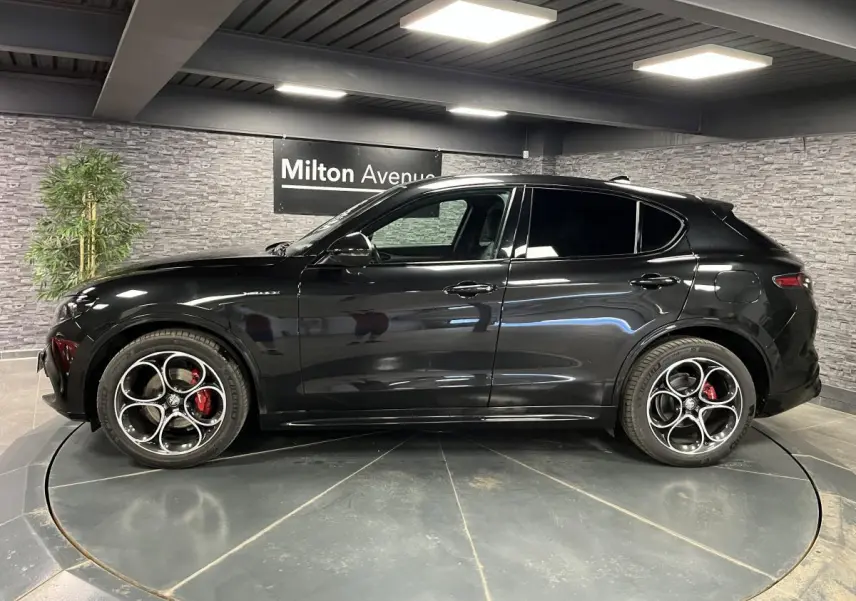 Vue latérale droite de l'Alfa Romeo Stelvio Veloce noire avec jantes 20 pouces et étriers de freins rouges Brembo.