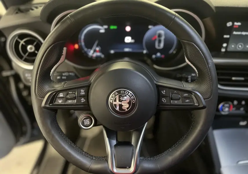 Vue rapprochée du volant sport en cuir noir de l'Alfa Romeo Stelvio 2024 avec commandes intégrées et tableau de bord digital.