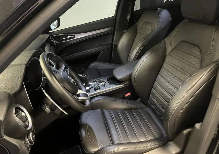 Vue intérieure côté conducteur de l'Alfa Romeo Stelvio Veloce 2024 avec sièges sport cuir noir et volant sport.