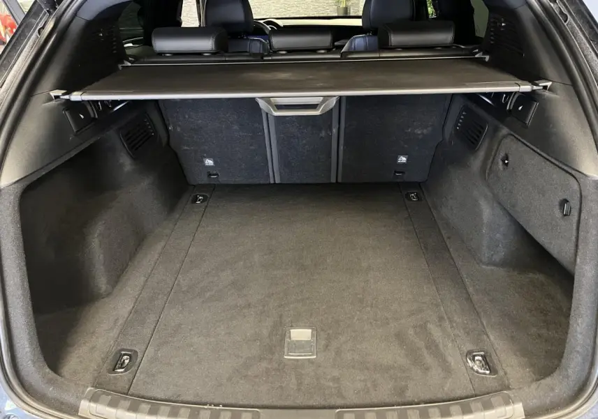 Vue du coffre arrière ouvert de l'Alfa Romeo Stelvio noir avec cache-bagages et banquette arrière visible.