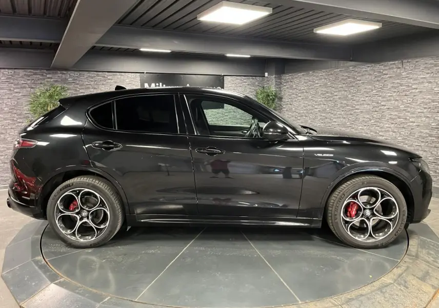 Vue de profil côté gauche d'un Alfa Romeo Stelvio Veloce noir métallisé avec jantes alliage 20 pouces et étriers rouges.