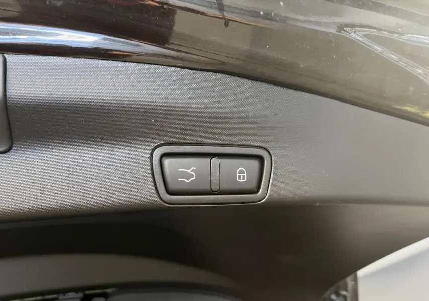 Gros plan sur le bouton d'ouverture et de verrouillage du hayon électrique du coffre d'un Alfa Romeo Stelvio noir.