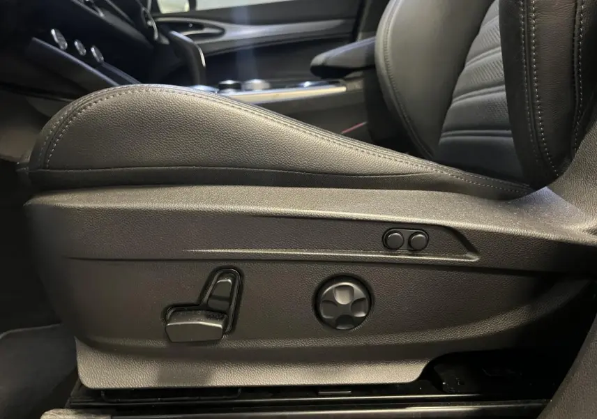 Gros plan sur les commandes de réglage électrique du siège avant en cuir noir de l'Alfa Romeo Stelvio Veloce 2024.