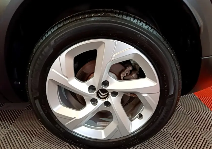Gros plan sur la roue avant droite avec jante argentée et logo Citroën sur un C5 Aircross noir.