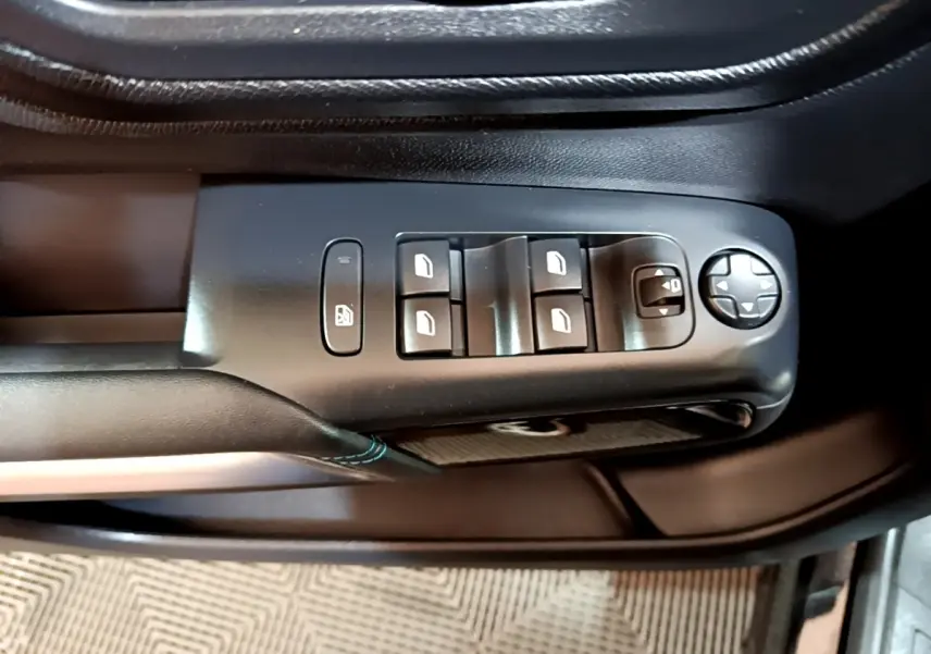 Gros plan sur les commandes de lève-vitres et réglage des rétroviseurs côté conducteur d’un Citroën C5 Aircross noir 2022.